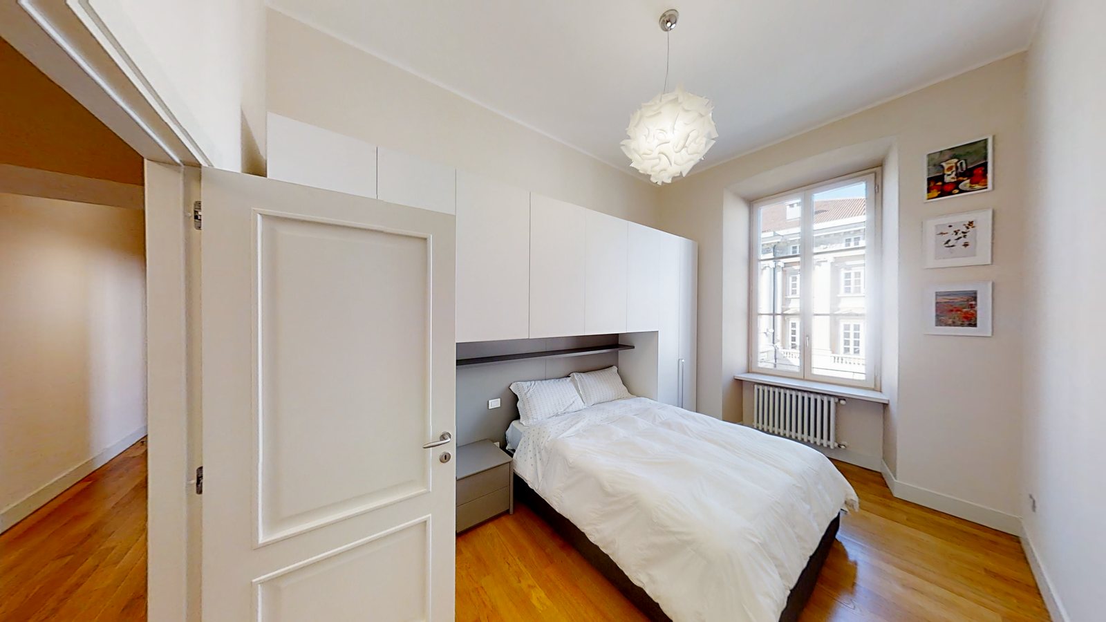 Zimmer mit Bett unter einem weißen Brückenschrank und drei gerahmten Drucken, Palazzo Tergesteo, Triest