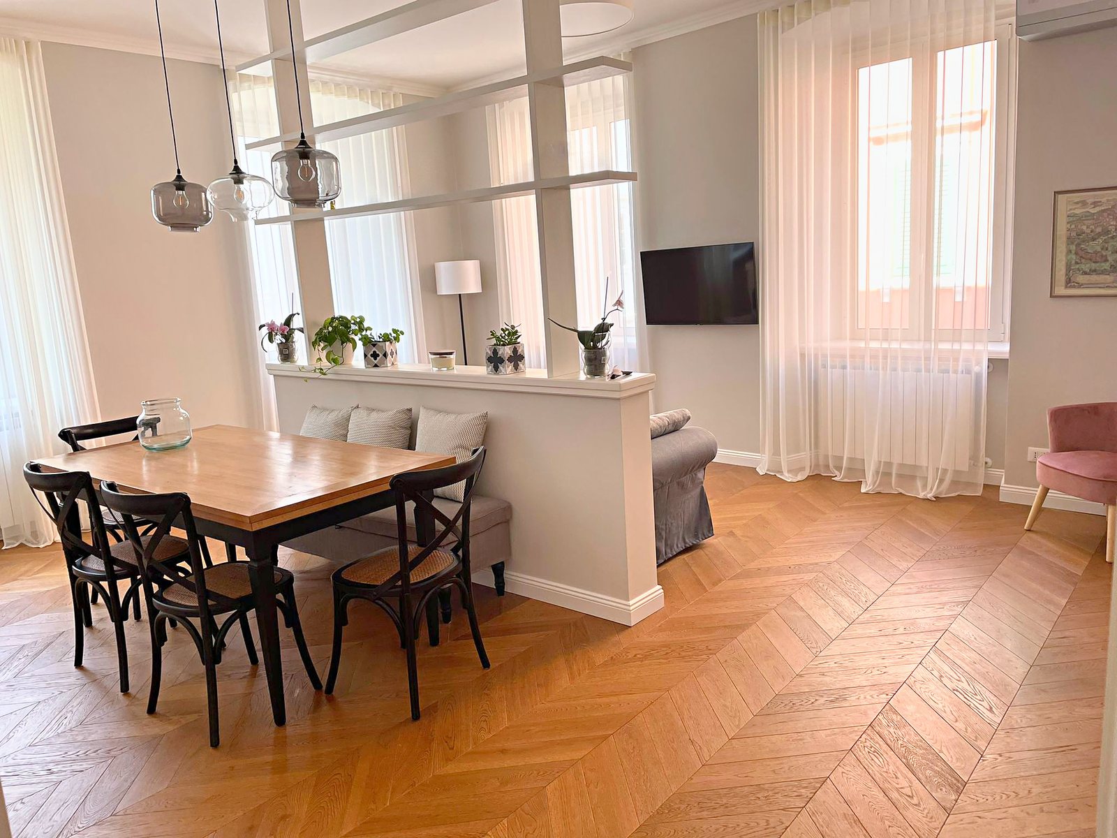 Zona pranzo con tavolo in legno, sedie nere e finestre alte con tende bianche, Via del Lazzaretto Vecchio, Trieste