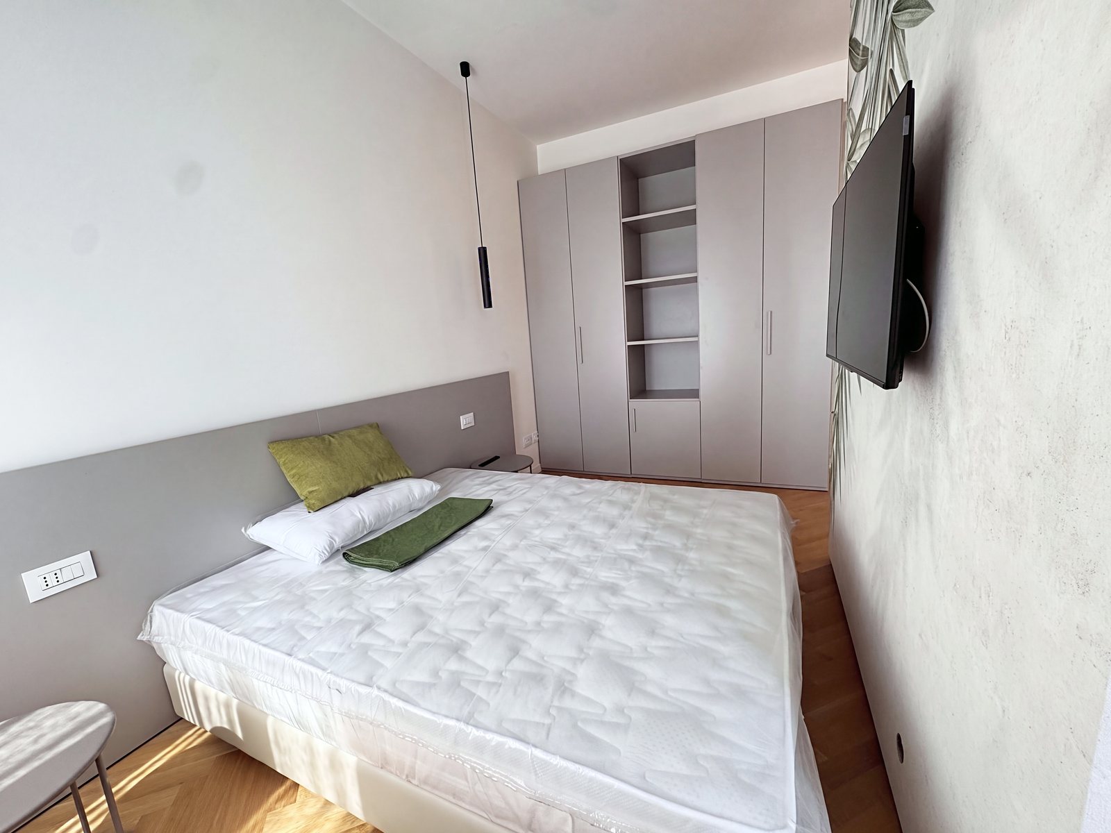 Zona notte con letto matrimoniale, testiera grigia e armadio con ripiani a giorno, via Carducci, Trieste