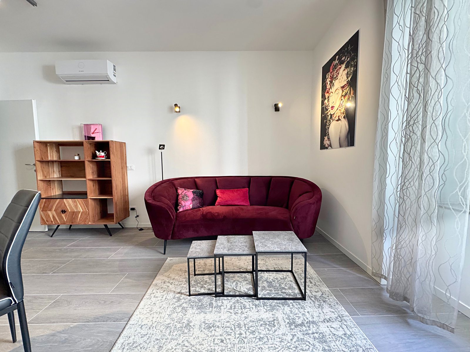 Divano in velluto bordeaux, libreria in legno e grande quadro, soggiorno arredato in via del Lavatoio, Trieste