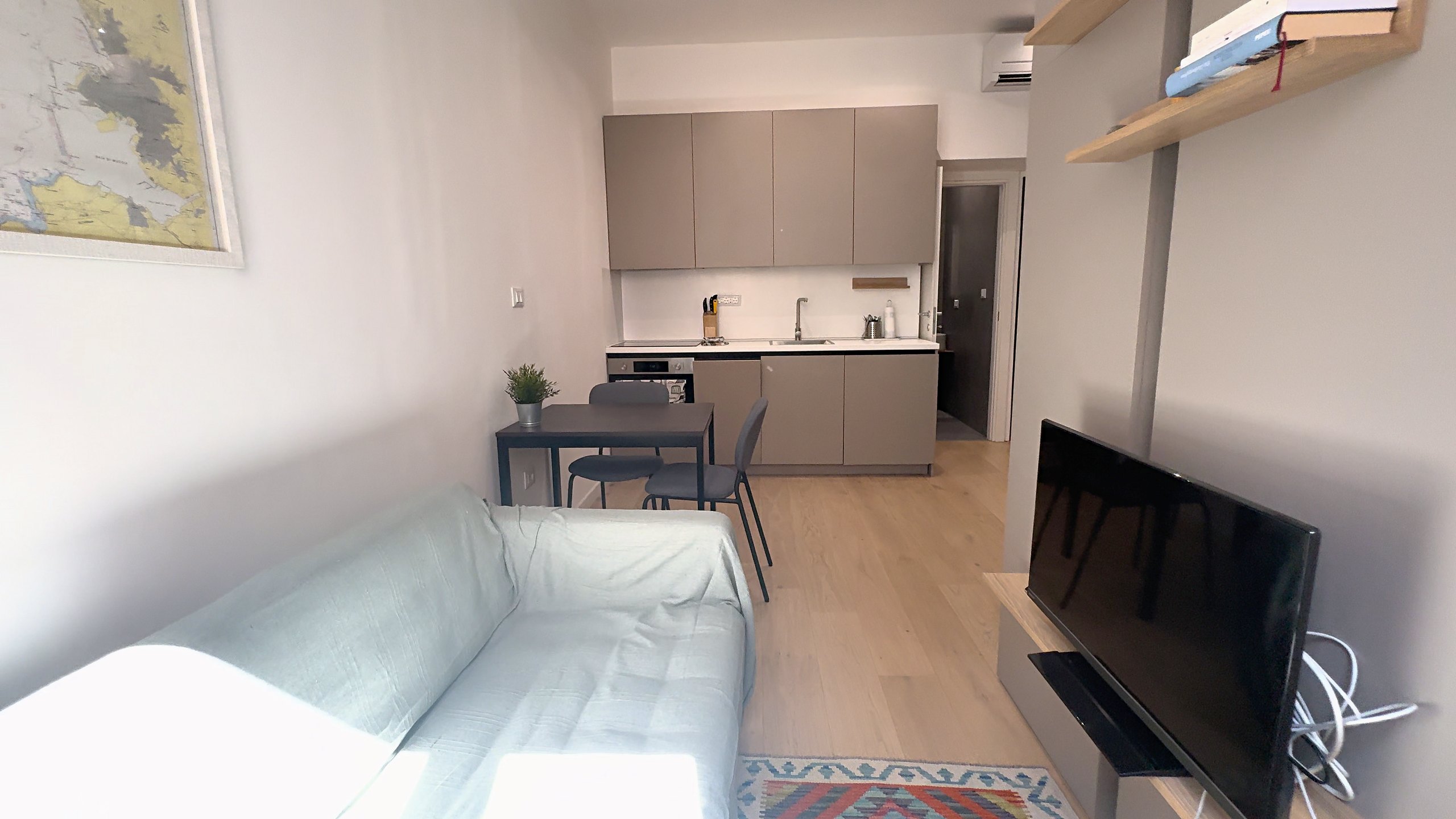 Möbliertes Studio: Sofa, Tisch für zwei und Küchenzeile im Hintergrund, Via della Madonnina, Triest