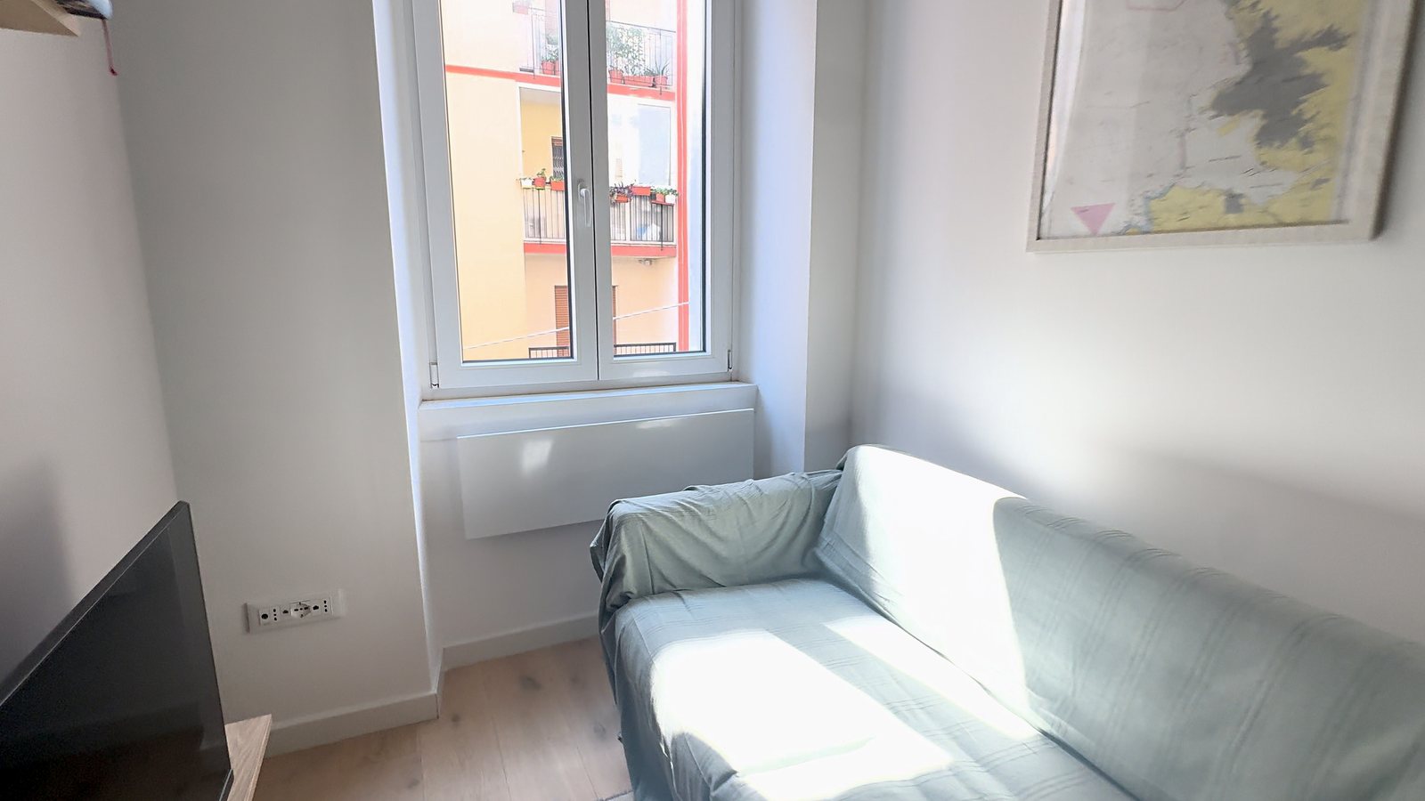 Wohnecke mit Sofa, Fenster zur Straße und gerahmter Landkarte, Via della Madonnina, Triest