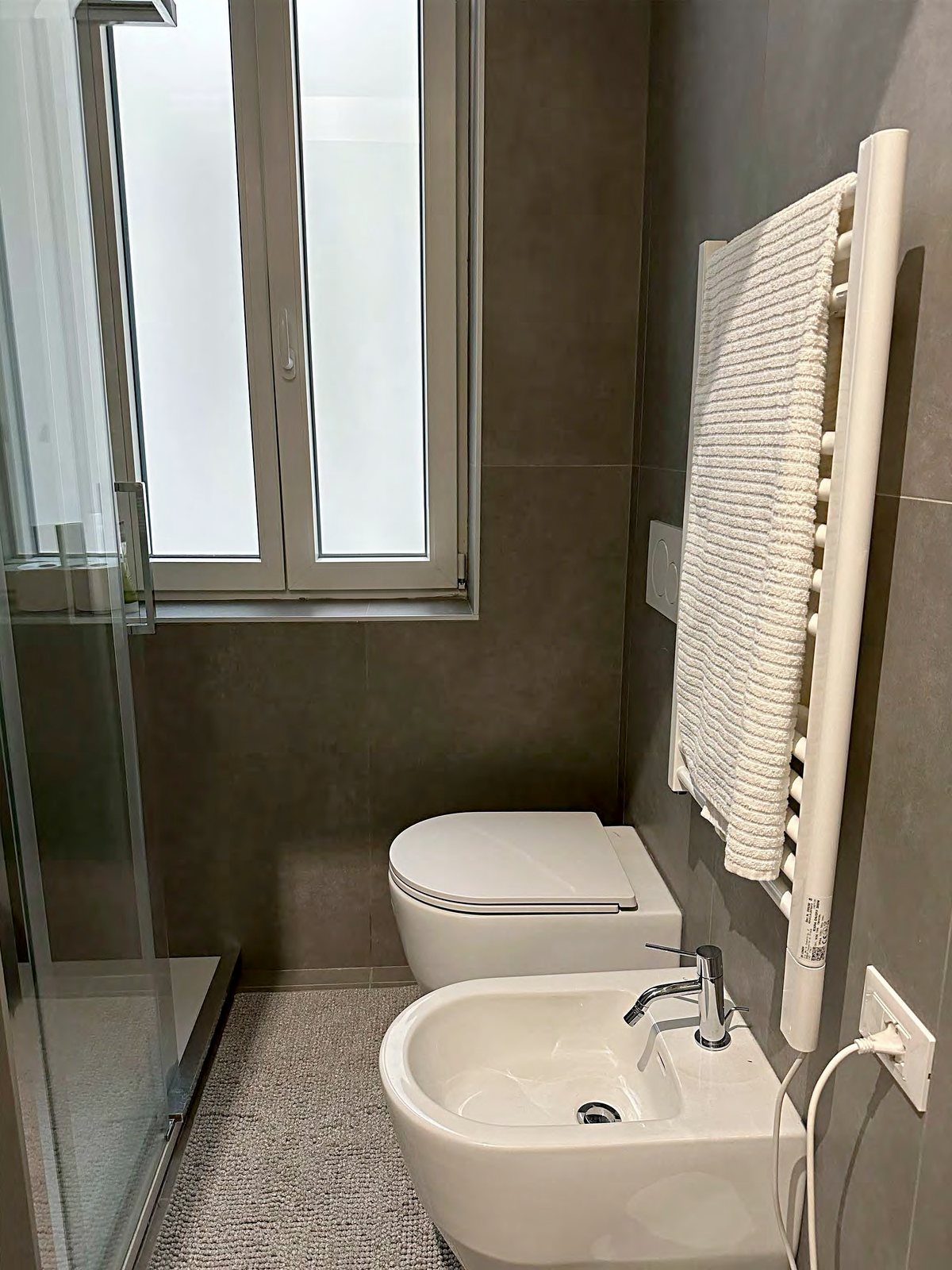 Bad mit Fenster, Hänge-WC und Bidet, Handtuchheizkörper und Glasdusche, Via della Madonnina, Triest