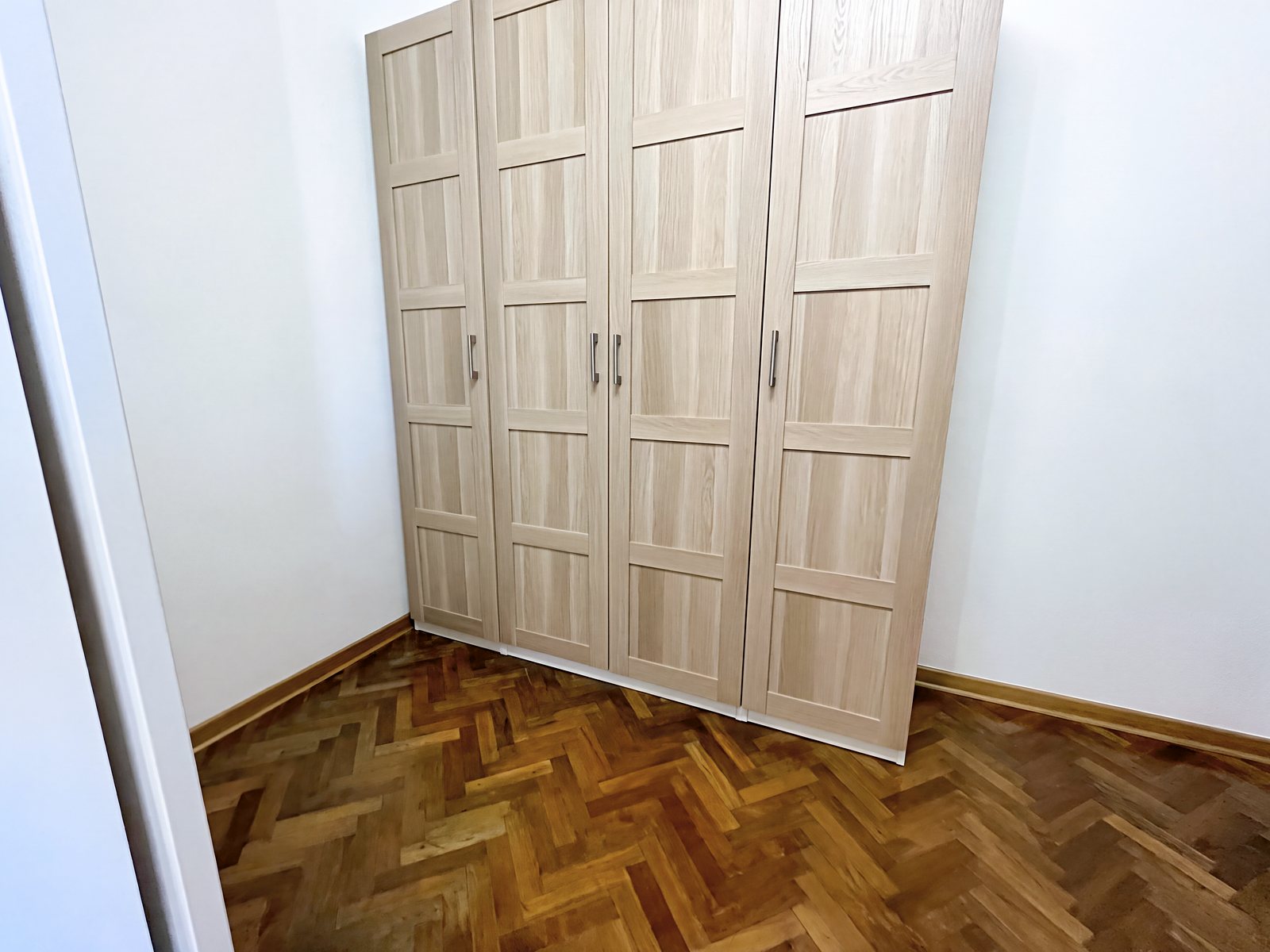 Soba s štirikrilno omaro iz svetlega lesa in parketom v ribji kost, Via della Fornace, Trst