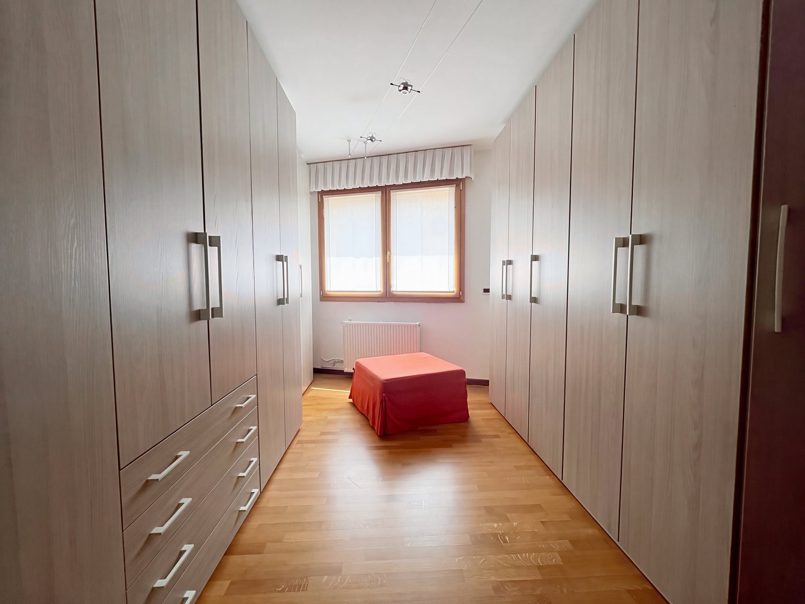 Soba z vgradnimi omarami iz svetlega hrasta in koralnim taburejem-ležiščem pod oknom, Via Tor San Piero, Trst
