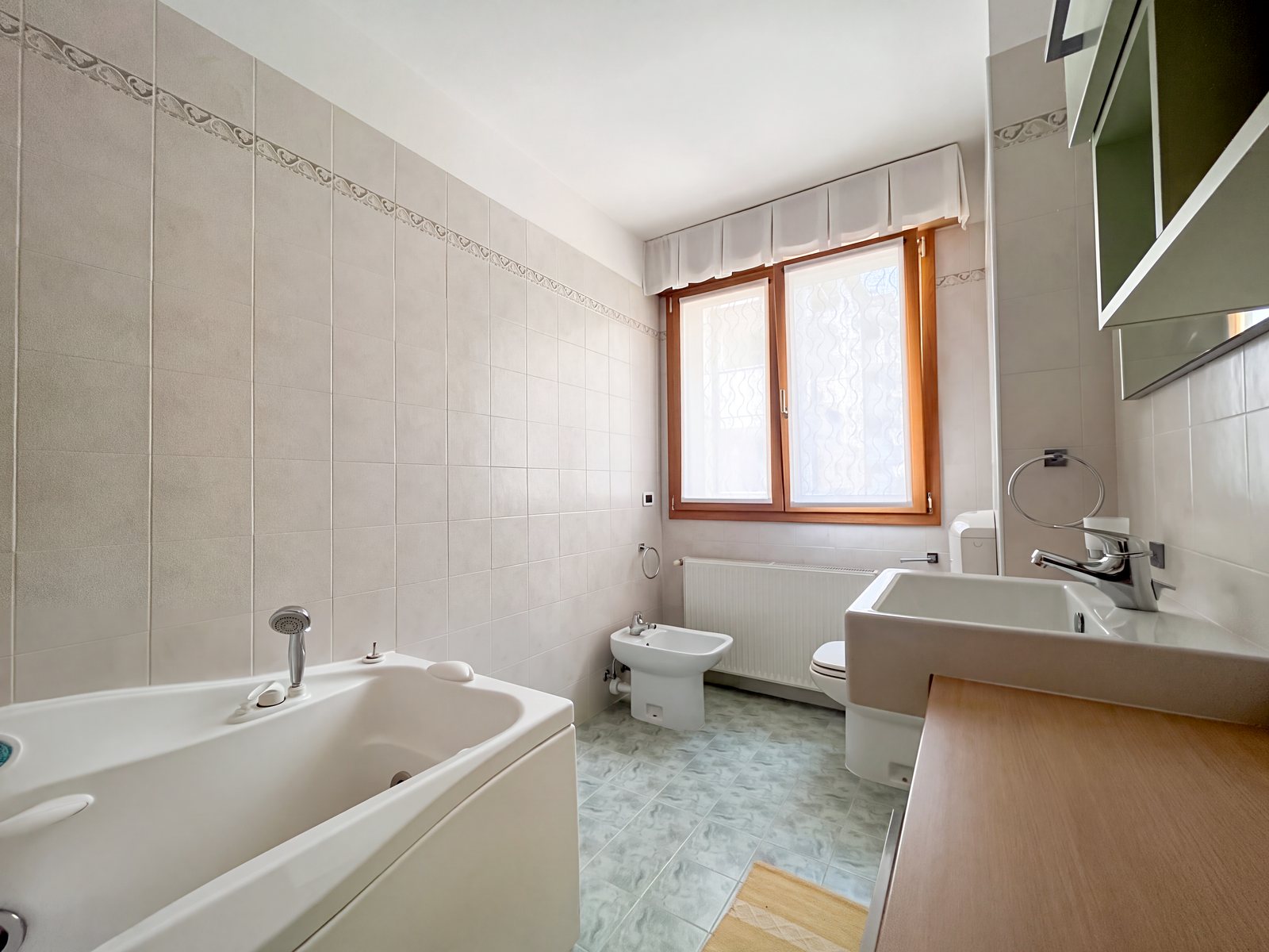 Kopalnica z masažno kadjo, bež ploščicami z borduro in oknom, Via Tor San Piero, Trst